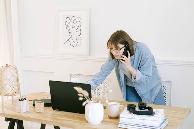 Person talking on a phone and looking at a laptop